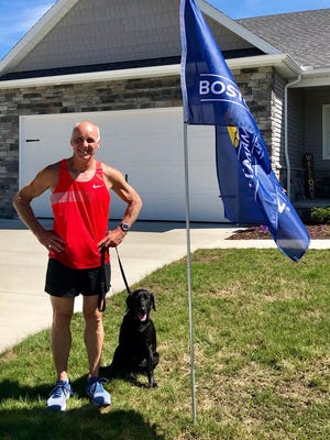 Mike Gintz and his dog Maggie pose by his 2020 Boston Marathon flag. Photo courtesy of Holly Valot