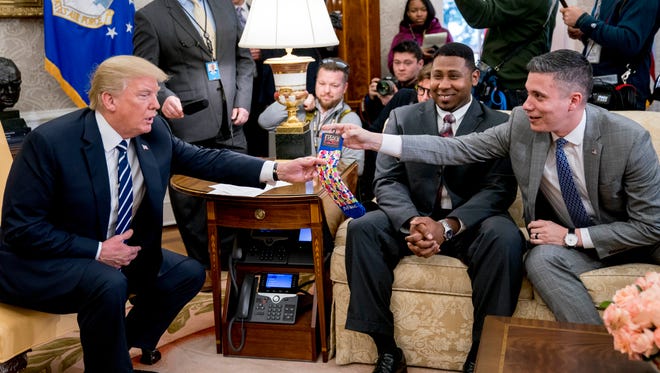 President Trump is handed a pair of Aflac socks by Michael Porter of Columbus, Ga., during a meeting with American workers on the impact of the tax reform bill in the Oval Office Wednesday.