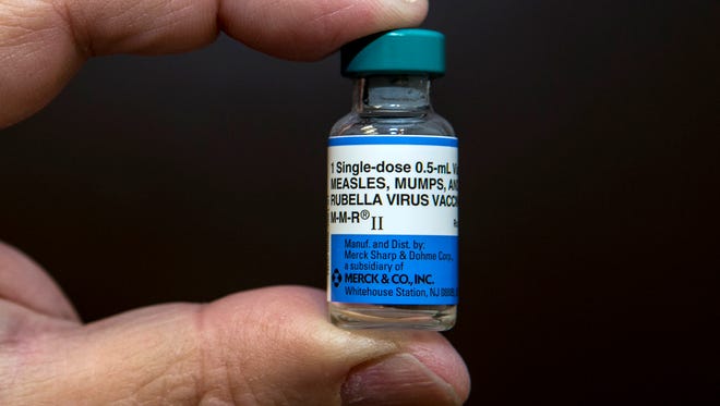 In this 2015 photo, a pediatrician holds a dose of the measles-mumps-rubella, or MMR, vaccine.