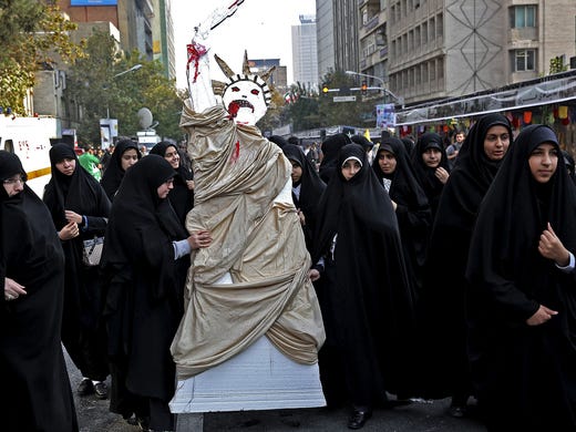 Iranian women display a bloody Statue of Liberty effigy.