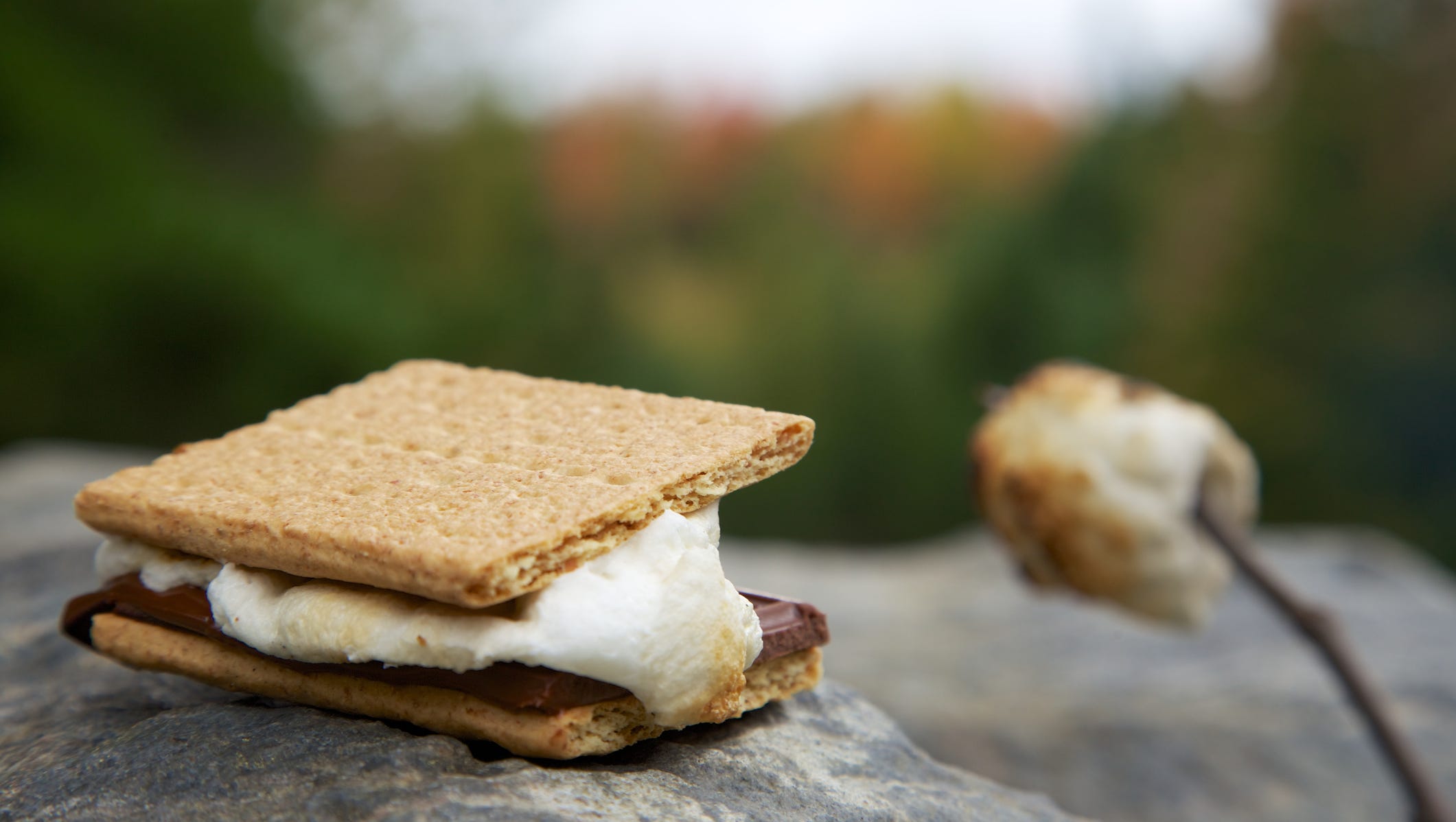 A perfectly melty s'mores treat rests on a boulder with a deliciously browned marshmallow nearby.