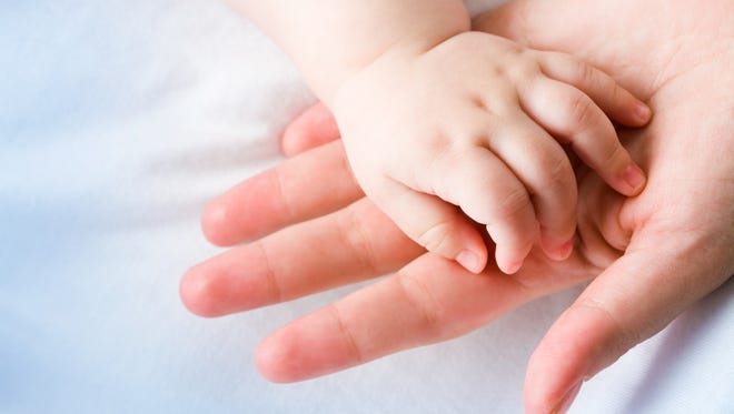 Image of moms palm with newborn baby hand on its surface