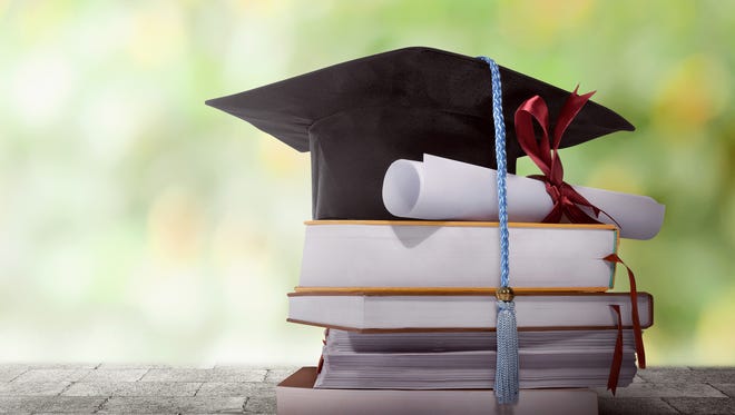 Graduation hat with degree paper on a stack of book against blurred background