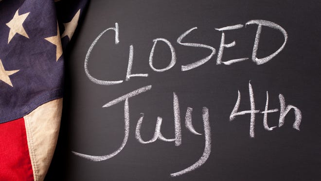 A "CLOSED July 4th" sign handwritten on a black chalkboard with vintage American flag.