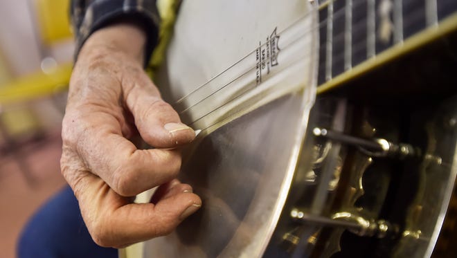 Dick Boschert plays a four-string banjo from the 1920's on a stage inside of Beck and Benedict Hardware store on Friday, Dec. 18, 2015. Boschert's banjo once belonged to his father.