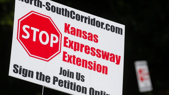 A number of "Stop Kansas Expressway Extension" signs can be seen on Farm Road 145 near the intersection with Weaver Road.