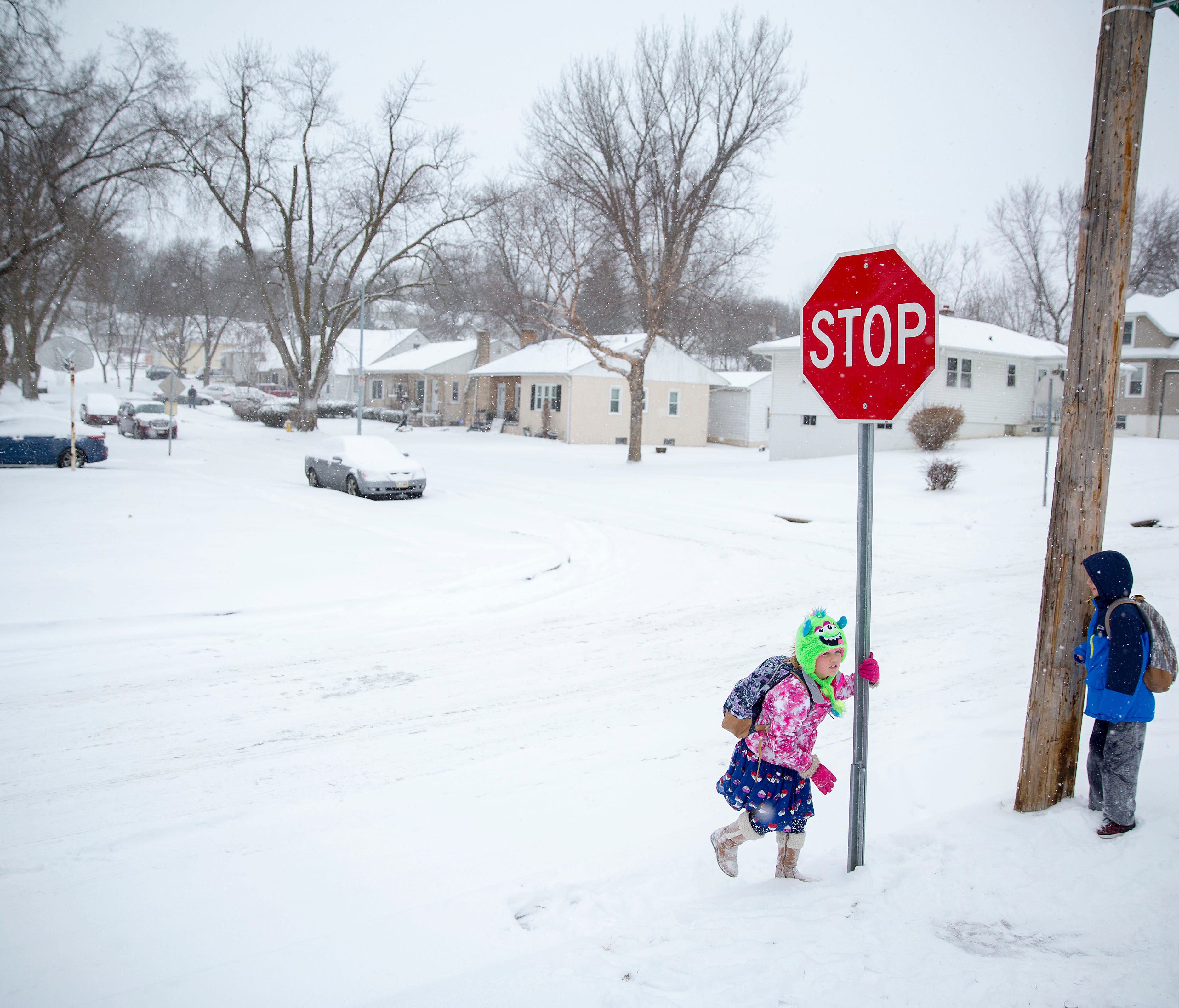 Mila Hunt (L) and her brother Alex (R) wait for their late-running school bus Wednesday in Omaha, Neb.
