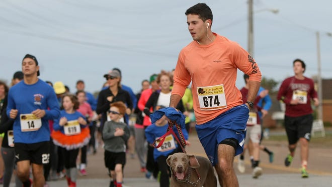 Thomas McLemore runs with his brother-in-law's dog Lilly during the 11th annual Turkey Day 5K on Thursday morning.