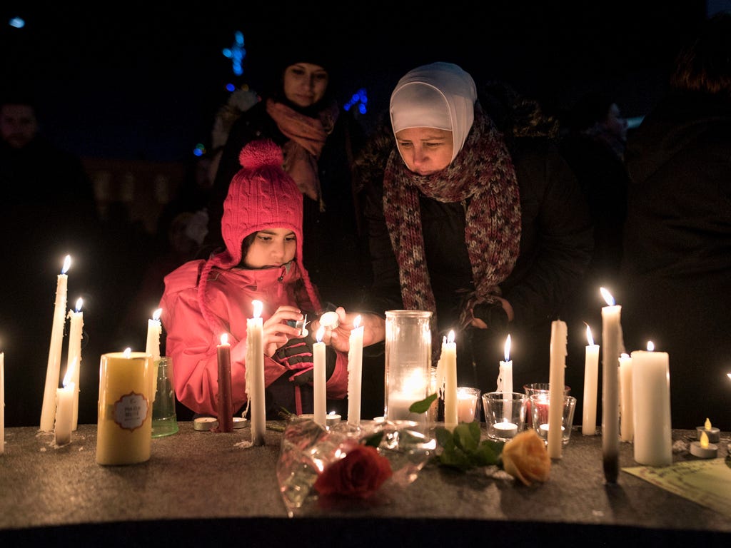 Sawsan Idris, right, lights candles with her daughters Lara and Tamara while attending a vigil in Moncton, New Brunswick, Jan. 30, 2017, for victims of the shooting at a Quebec City mosque.