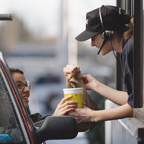Fast-food restaurant worker handing food to a driv