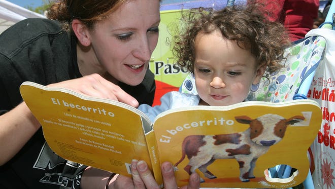 Katherine Padilla shows daughter Raven Padilla, 21 months, a book she received during a previous Día de los Niños, Día de los Libros celebration at Washington Park.