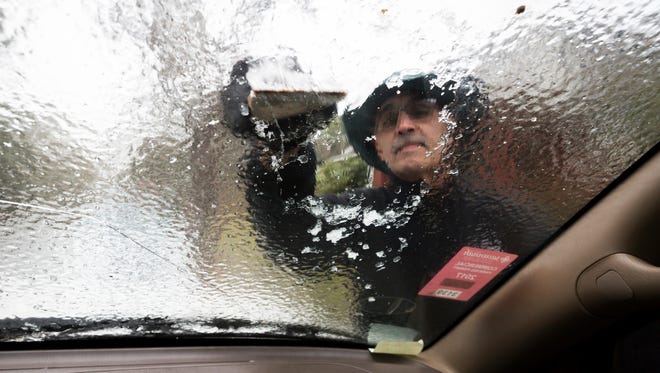 Omar Elkhalidi uses a wood shim to scrape ice off his windshield that accumulated overnight from freezing temperatures, in Savannah, Ga. Jan. 3, 2018.