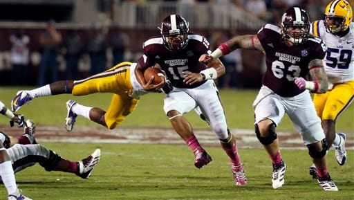 Mississippi State quarterback Dak Prescott (15) dodges an LSU defender as teammate offensive linesman Dillon Day (63) leads his run in the second half of their NCAA college football game in Starkville, Miss., Saturday, Oct. 5, 2013. No. 10 LSU won 59-26. (AP Photo/Rogelio V. Solis)