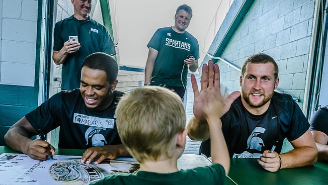 MSU tight end Matt Sokol high-fives a young autograph-seeker during the Meet the Spartans event Tuesday at East Lansing.