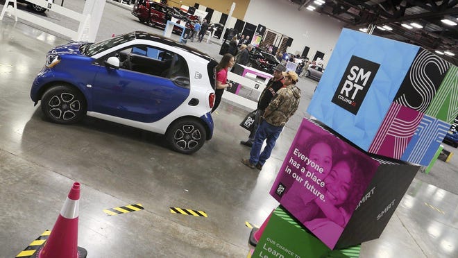 Mackenzie Lawrence of Smart Columbus talks up the benefits of electric car to Jim Ryan, center, and his son, also Jim Ryan, of Delaware at the  Columbus Auto Show in 2018.