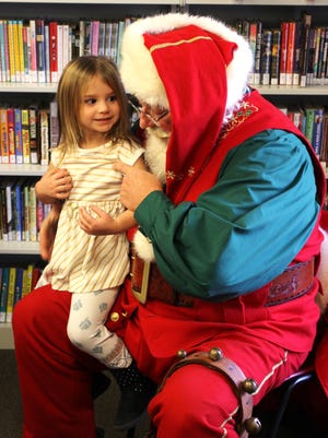 Santa Claus asked Mackenzie Wharton, 3, of Etna, what she wanted for Christmas during his visit to the Pataskala Public Library.