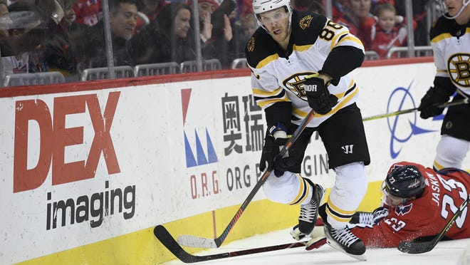 Bruins defenseman Kevan Miller (left) chases the puck against Capitals right wing Dmitrij Jaskin during the second period of a NHL hockey game on Feb. 3, 2019, in Washington. Despite not playing in a game for the last 14 months, Miller has been nominated for the Bill Masterton trophy.
