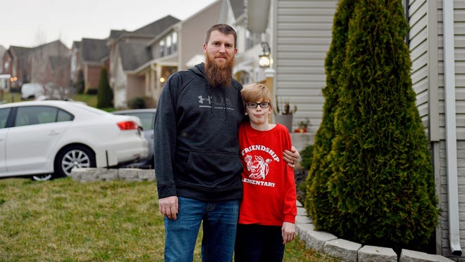Joe Kirby, 34, stands for a portrait with his son, Joey, 10, outside their home in Codorus Township. After Kirby and his wife, Christina, failed to pay their trash bill to Penn Waste and were taken to court, the company sent a deputy sheriff to the house.