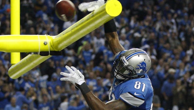 Calvin Johnson dunks the ball over the goal post after his third-quarter touchdown against the Green Bay Packers in Detroit on Nov. 28, 2013.
