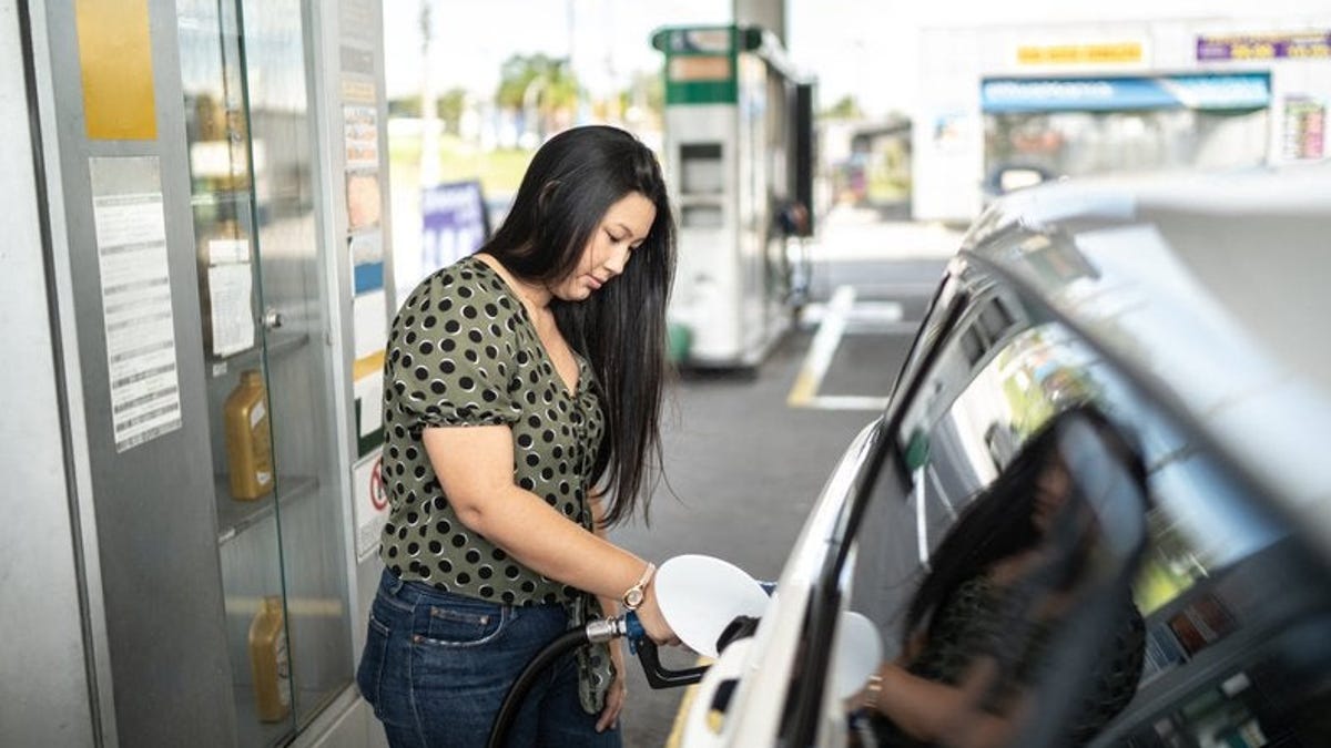 Woman refueling her car at a gas station.
