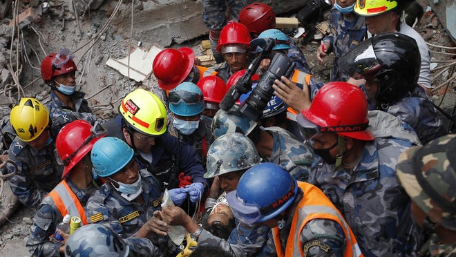 Pemba Tamang is carried on a stretcher after being rescued by Nepalese policemen and U.S. rescue workers from a building that collapsed in Kathmandu, Nepal. Crowds cheered on Thursday, April 30, 2015, as Tamang was pulled, dazed and dusty, from the wreckage of a seven-story Kathmandu building that collapsed around him when a massive earthquake shook Nepal.