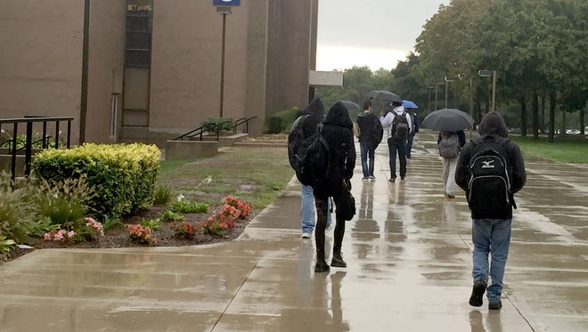 Macomb Community College students at the Warren campus using umbrellas and hoods to cover themselves from rain as they walk Sept. 29, 2016. Christina Hall/Detroit Free Press