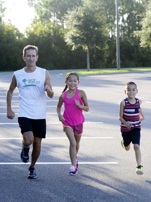 Steve Hedgespeth and his children; Colin, 7, and Kara, 9, run at Rodes Park in West Melbourne.