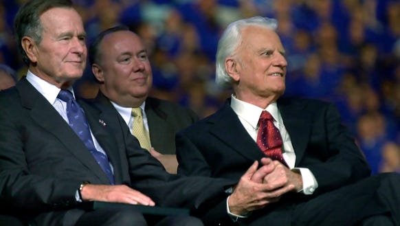 The Rev. Billy Graham, right, grasps the hand of former