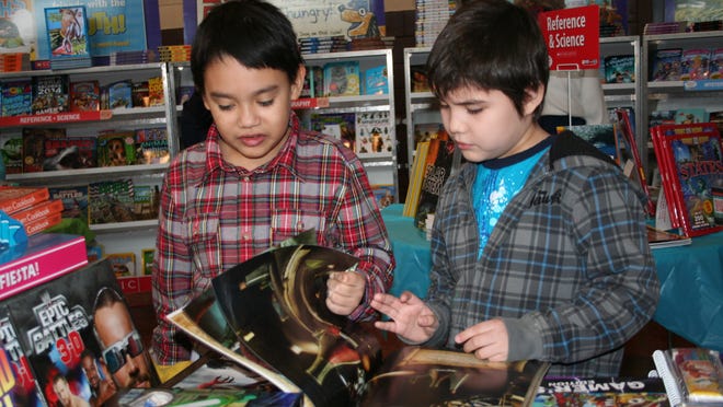 In this file photo from 2014, Randolph Ochoa and Derick Lira glance through a science-themed book at a Scholastic Book Fair at St. Gregory School in St. Nazianz.