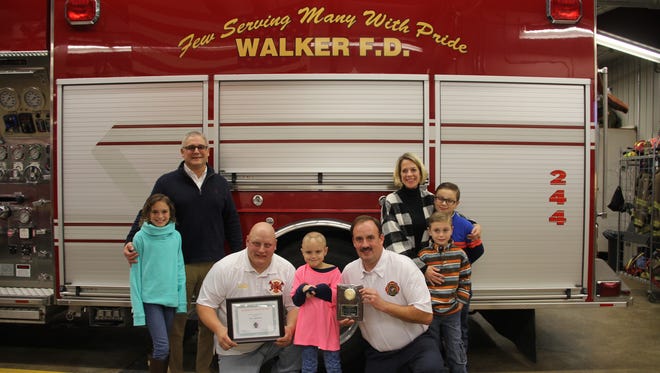 Eva Bruno, 6, (center) became an honorary member of the Walker Fire Department on Nov. 12, 2017.  In this photo she is joined by her family and the department’s president Chris Flugel (bottom left) and chief Jim Hushard (bottom right).