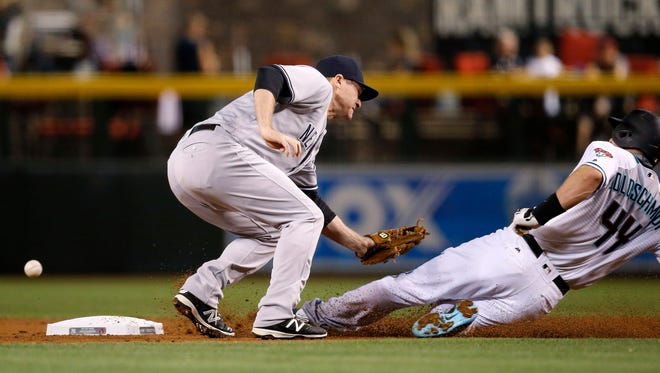 Arizona Diamondbacks' Paul Goldschmidt (44) slides safely into second base as New York Yankees' Chase Headley, left, misses the baseball for a field error during the first inning of a baseball game Tuesday, May 17, 2016, in Phoenix. The Diamondbacks' Goldschmidt advanced to third base on the play.