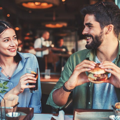 A man and woman eating hamburgers in a restaurant.