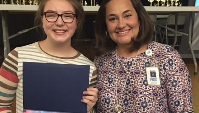 South Middle School's Kendall Pullum, left, displays her certificate for winning the 7th grade division of KET's 2018 Young Writers Contest, which was presented by KET's Amy Grant, right.