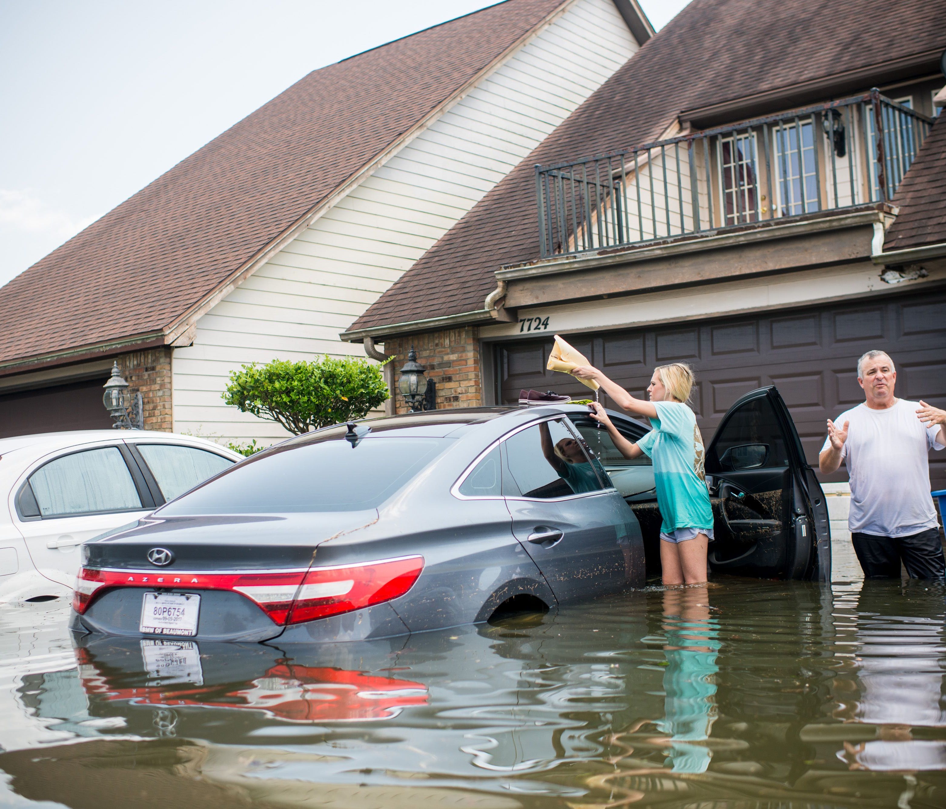 Jenna Fountain and her father Kevin check her flooded car outside their home in Port Arthur, Texas