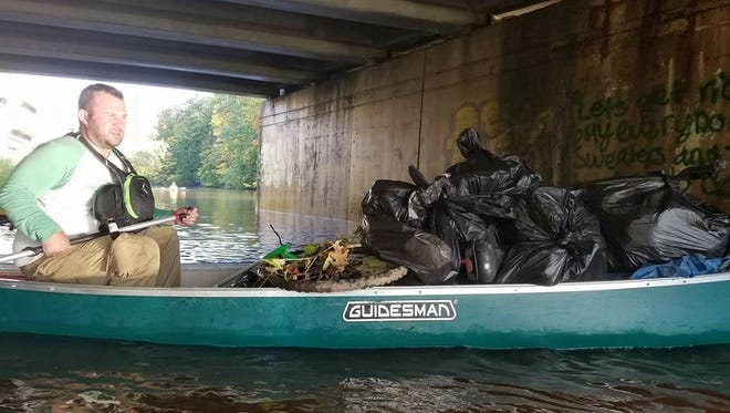 Nate Williams, co-owner of River Town Adventures, a kayak rental business at the Lansing City Market, paddles along with trash picked up Monday. River Town organized an impromptu river cleanup after Joe Hertler discovered trash floating in the Red Cedar Saturday.