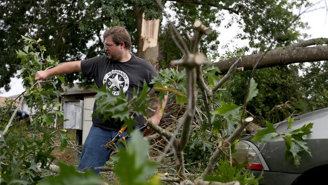 Micah Armer clears a large branch that fell on his neighbor’s car Saturday after strong wind gusts in east Salem.