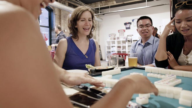 Members of the Philly Mah-Jawng Club teach Sarah Wright, center, and Kiu Lau, far right, how to play the game over the summer at ThirstyDice in the Spring Garden section of Philadelphia. At left, a player makes a move.