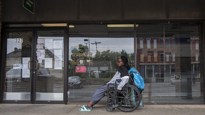 Sannette Davis from nearby 21st Street, pushes her wheelchair past the closed Mt. Vernon post office location in Columbus, Ohio, on Sept. 2.