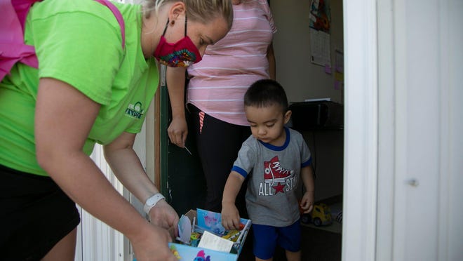 Molly Spaak, a law clerk with Migrant Legal Aid, checks in with residents in migrant camps to hand out PPE and advocacy materials plus toys to Isaac Martinez, 2, Monday Aug. 31, 2020. For many immigrants, the COVID-19 pandemic has heightened risks and inequities typically faced while living in the U.S.
