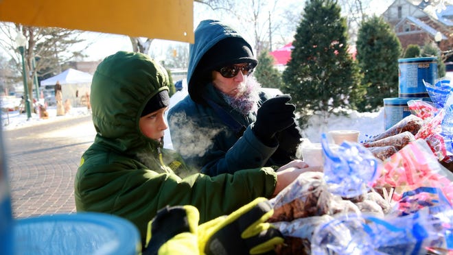 Linda Brandt, 66, of Troy and her grandson, Grady Tait, 8, of Lake Orion grab a hot apple cider during the Plymouth Ice Festival.