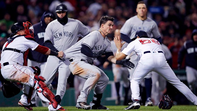 New York Yankees' Tyler Austin, center, rushes Boston Red Sox relief pitcher Joe Kelly, right, after being hit by a pitch during the seventh inning of a baseball game at Fenway Park in Boston, Wednesday, April 11, 2018. At left holding back Austin is Red Sox catcher Christian Vazquez.
