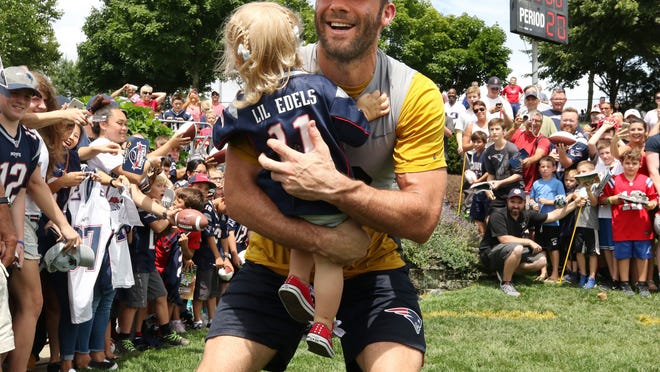 Patriots receiver Julian Edelman scoops up his young daughter, Lily Edelman, during training camp in 2018. According to a report, the Patriots won't be back at Gillette until training camp opens in late July.