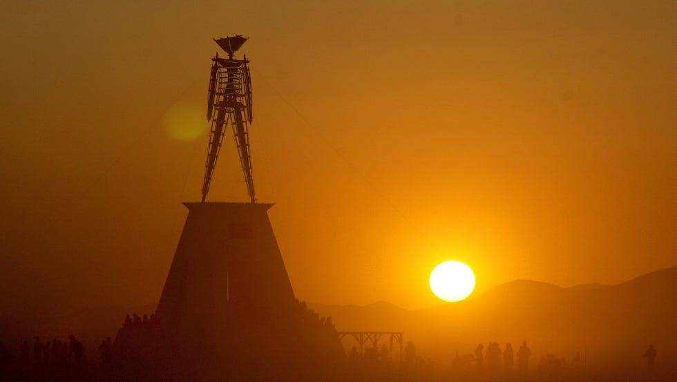 Participants in the annual Burning Man Festival hang out near the "Man" at sunrise on the Black Rock Desert near Gerlach, Nev., in 2001.