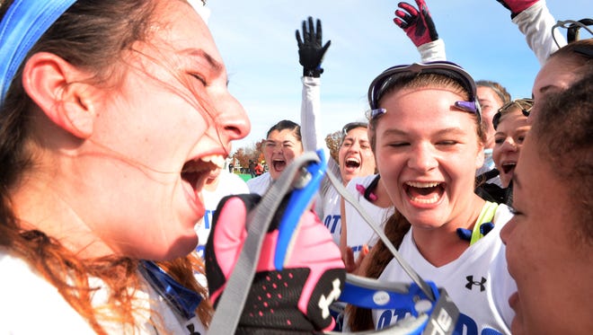 Otter Valley High School's Courtney Randall, from left, Maia Edmunds and Myliah McDonough celebrate its 1-0 victory over Mount Abraham Union High School in the Division II field hockey state championship game at the University of Vermont on Saturday, October 31, 2015.