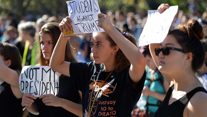 Albany High School senior Lulu Lebowitz, center, holds a protest sign as she and classmates Lily Hopwood, left,  and Tanan Javkhlantugs join others at U.C. Berkeley  Wednesday, Nov. 9, 2016, in Berkley, Calif.