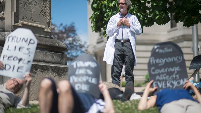 Robert Stone, a local doctor and member of Physicians for a National Health Program, oversees a handful of protesters as local concerned citizens gather to protest the current health care bill being considered in the Senate with a "Die-in" at the Monroe County Courthouse in Bloomington, Ind. Monday, June 26, 2017. (Chris Howell/The Herald-Times via AP)