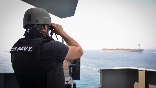 Gunner's Mate 3rd Class Jalen Delgado, from Boston, observes passing ships aboard the aircraft carrier USS Nimitz on Sunday in the Strait of Hormuz.