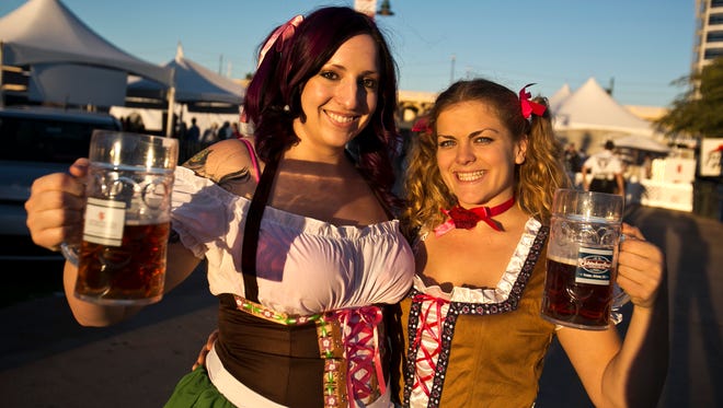Alison Conley and Amy Wellman hold up their beers while wearing dirnls at Oktoberfest.