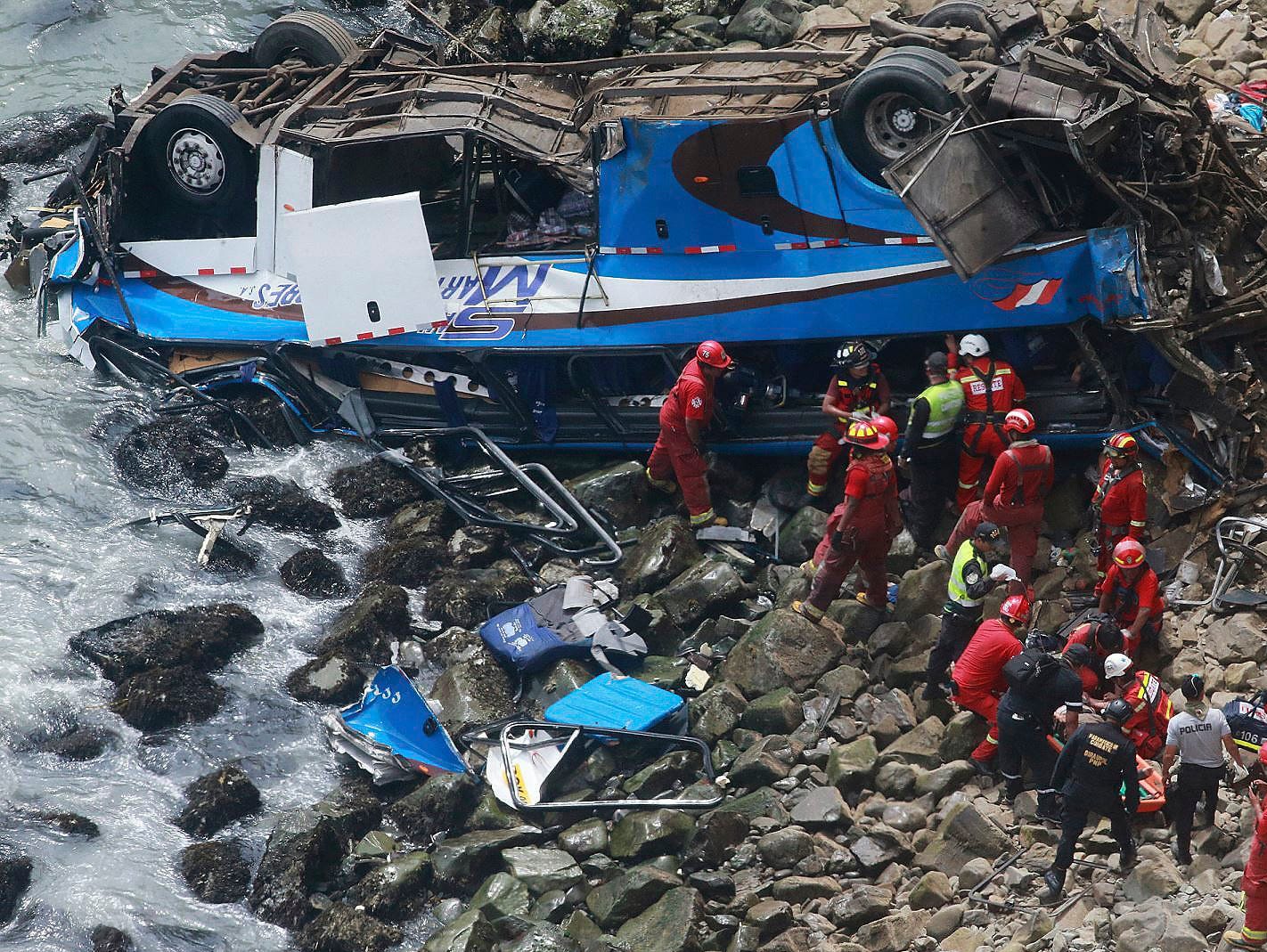 In this photo provided by the government news agency Andina, firemen recover bodies from a bus that fell off a cliff after it was hit by a tractor-trailer rig, in Pasamayo, Peru, Jan 2, 2018. A Peruvian police official says at least 25 people died, a