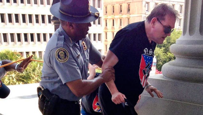 Police officer Leroy Smith, left, helps a man wearing National Socialist Movement attire up the stairs during a rally in Columbia, S.C. on July 18.